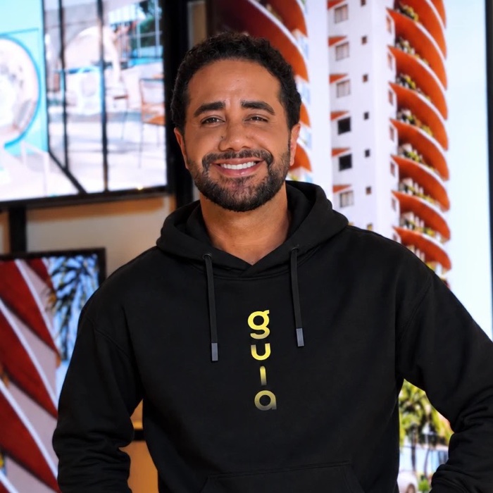 Victor Albuquerque, sorrindo, de moletom preto do Guia